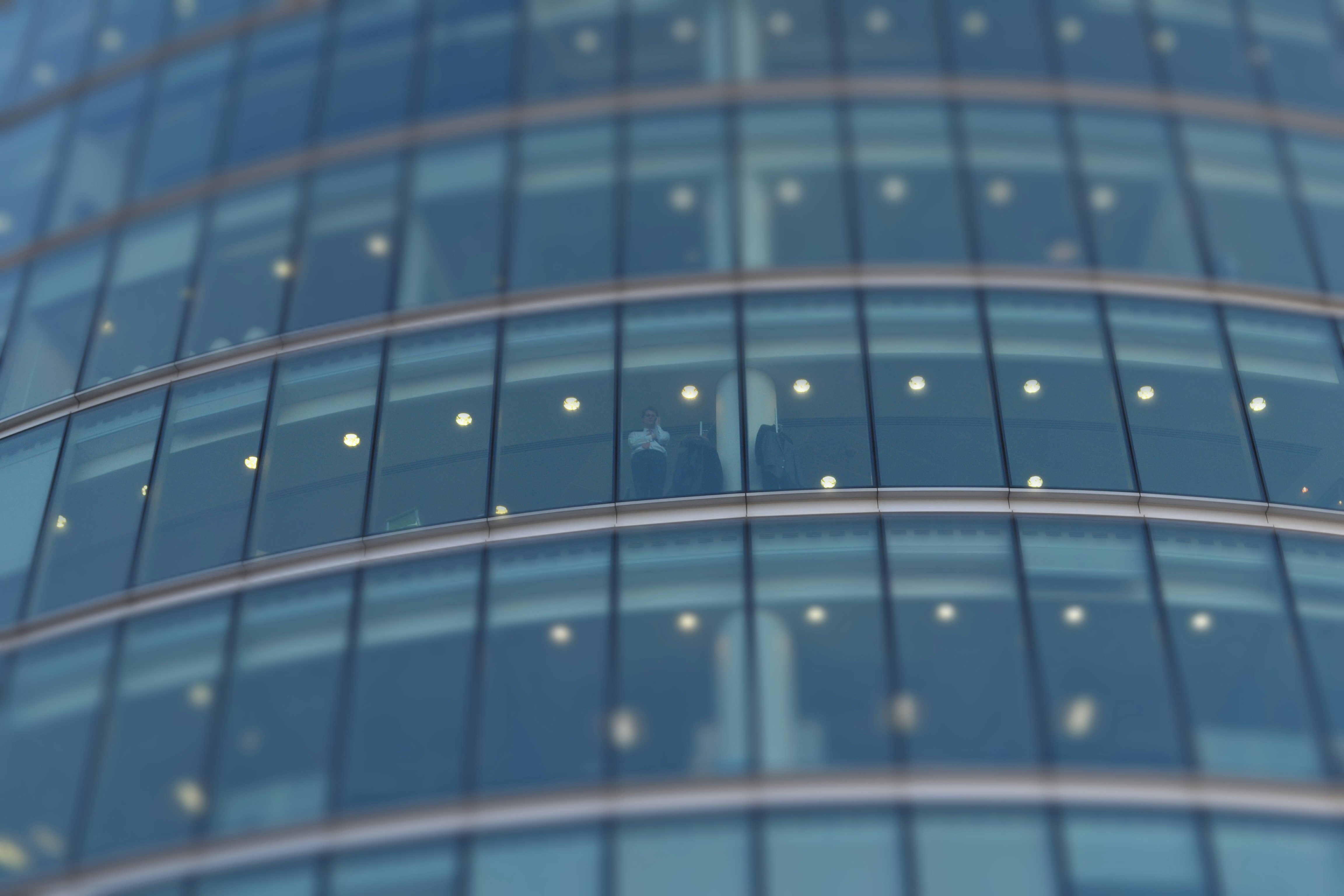 selective focus photograph of person standing near building glass curtain